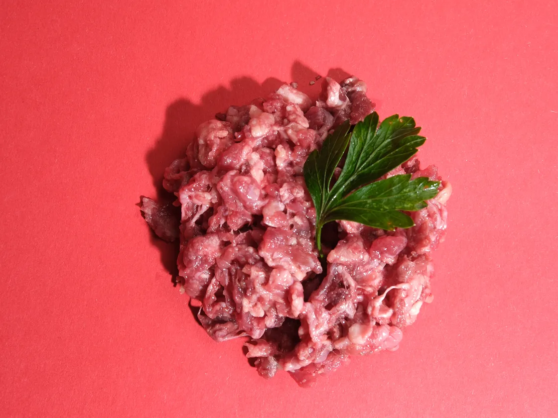 Portion rohes BARF-Hackfleisch mit einem Petersilienblatt